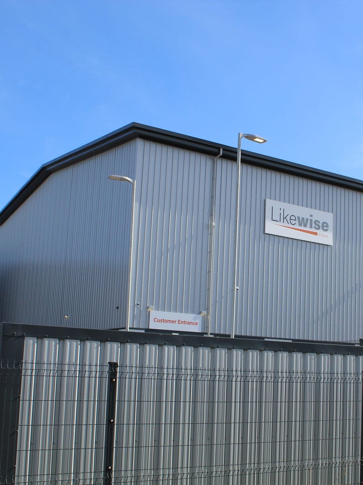 Silver wall cladding and the gable of a unit, behind a mesh fence