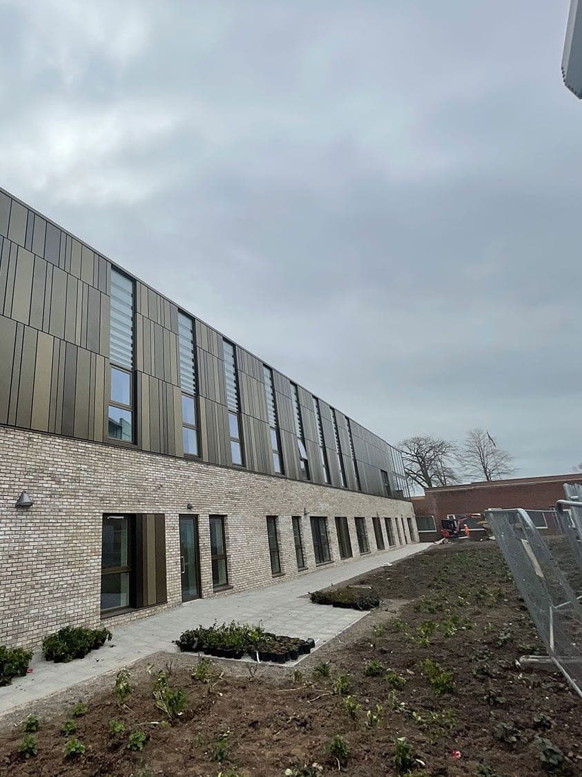 The long side of the centre: rainscreen panels above a brick base