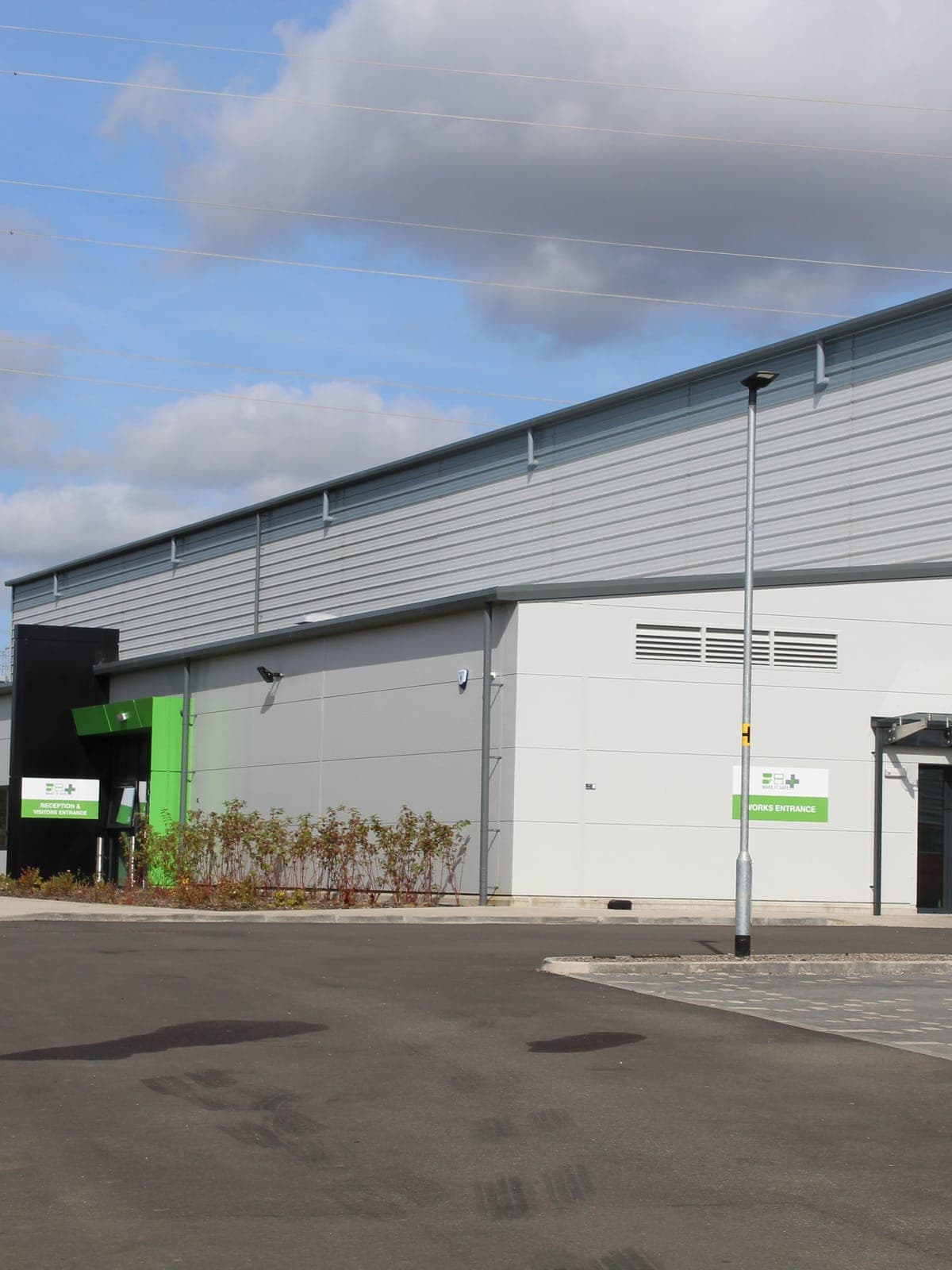 The long side of the factory, silver over dark grey, with the office entrance