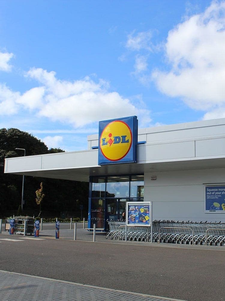 The Lidl store at Broxburn: white cladding over the glazed front, with the trolley shelter