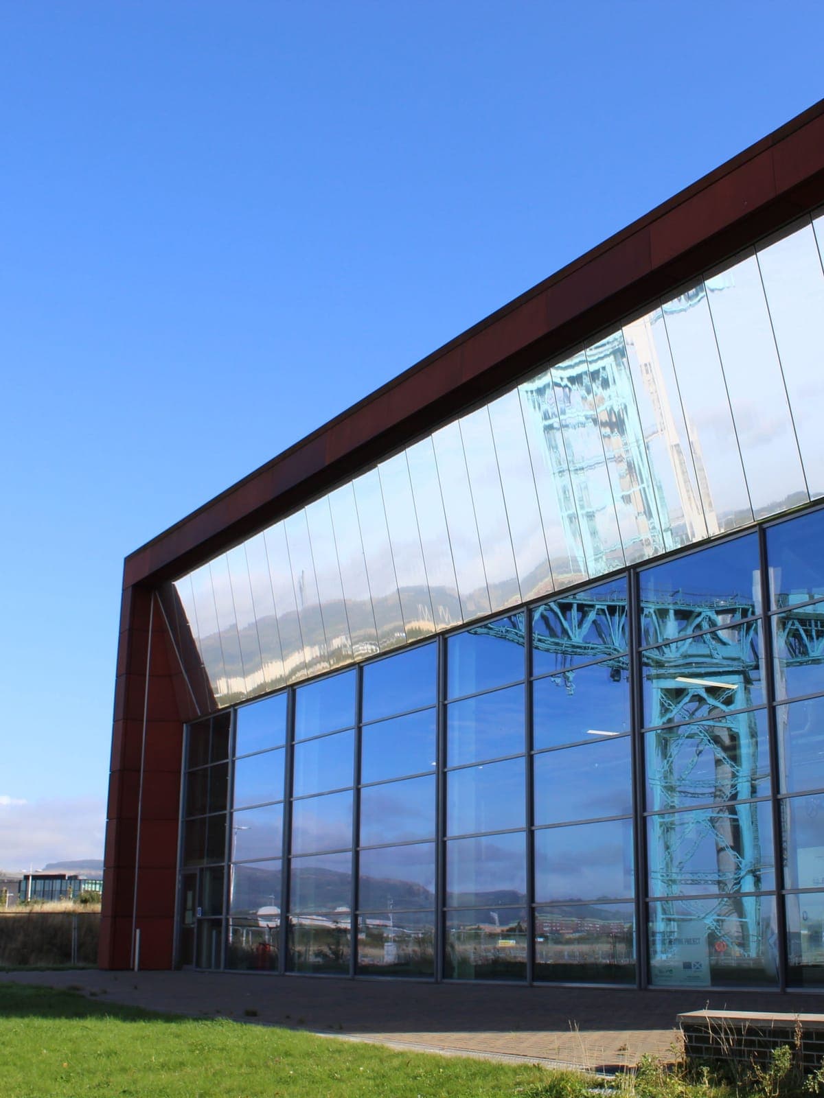 The corten-effect frame round the glazed front, with a crane reflected in the glass