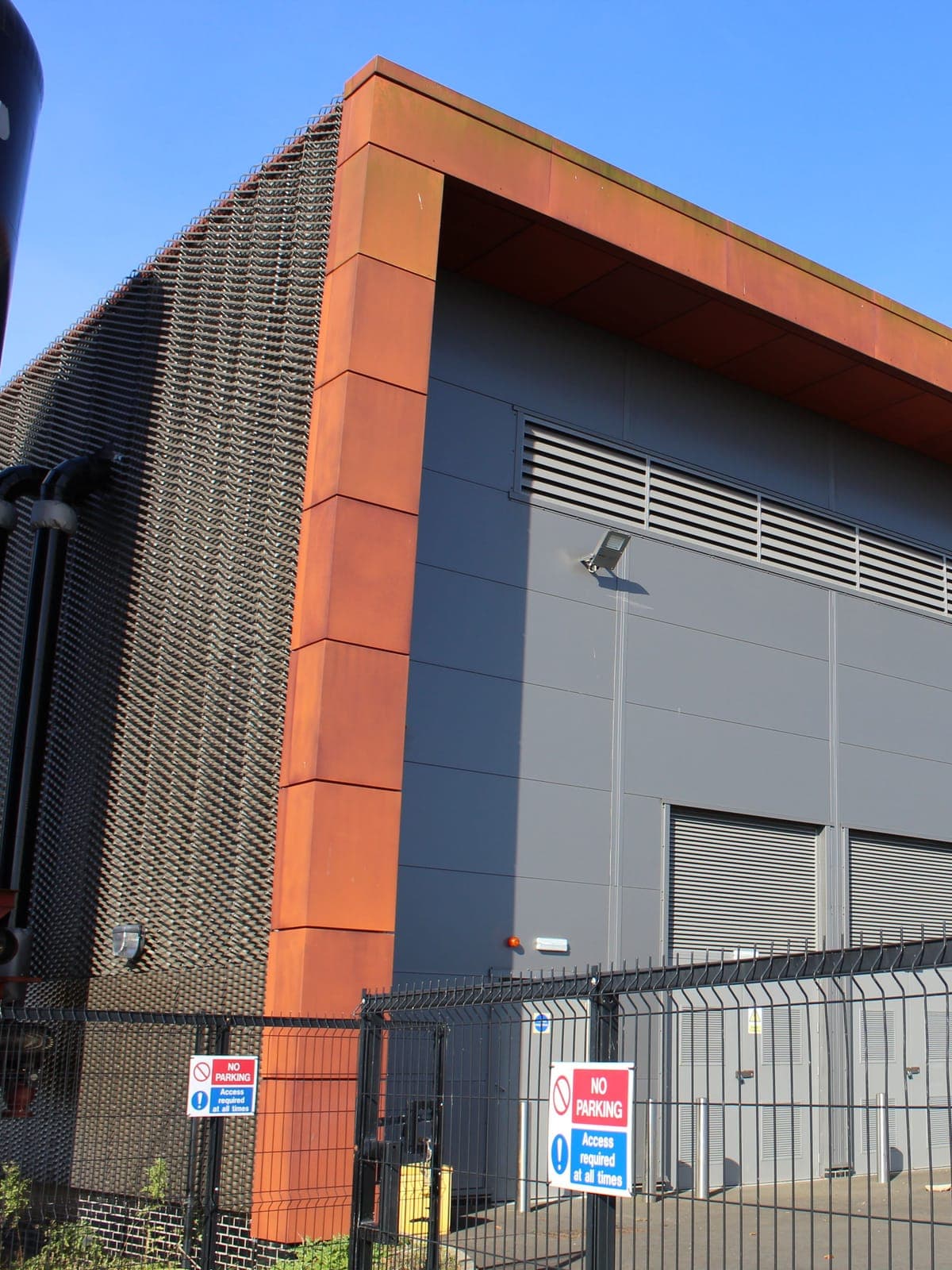 Grey wall cladding and louvres, edged by the corten-effect fascia