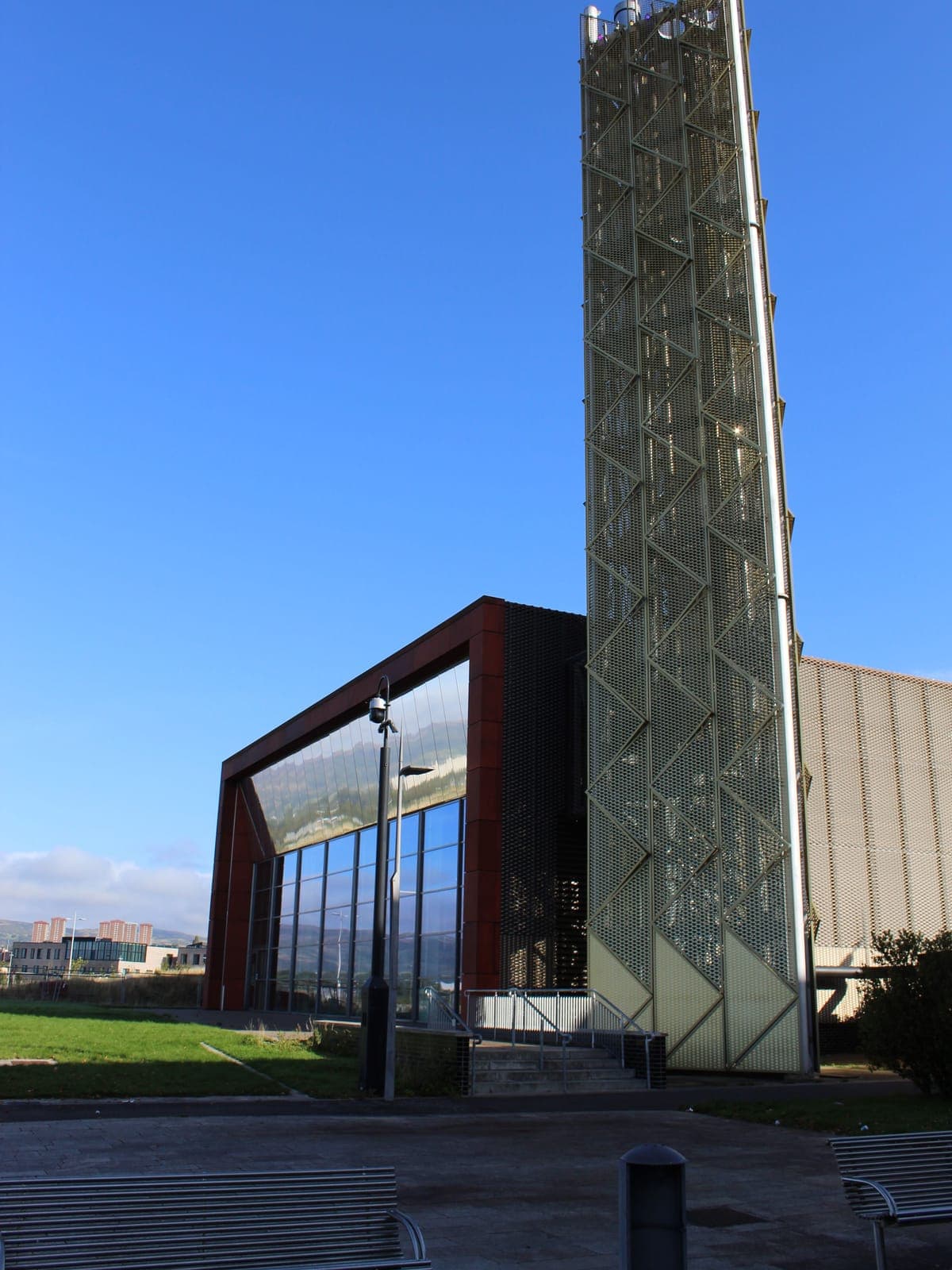 The Queens Quay energy centre: the mesh-clad flue tower beside the glazed hall in its corten-effect frame