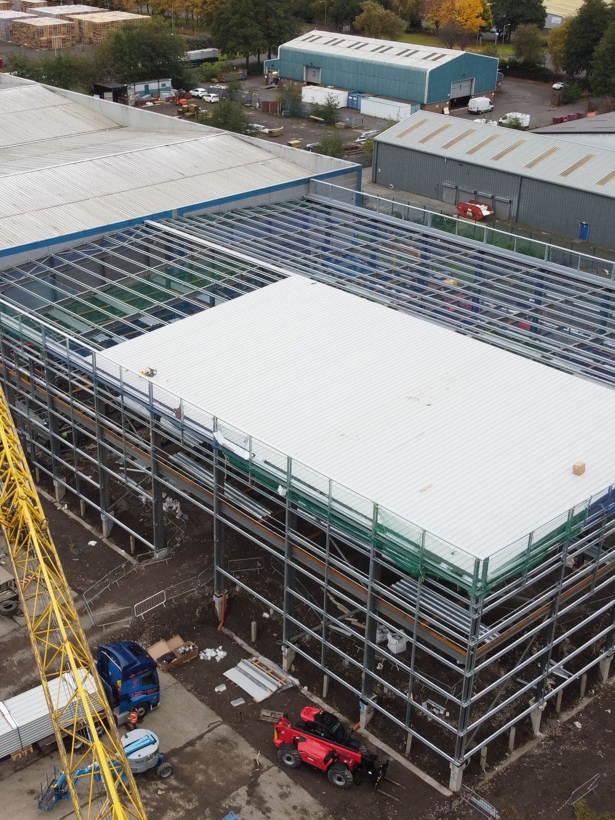 Roof sheets going on over part of the frame, with the crane alongside